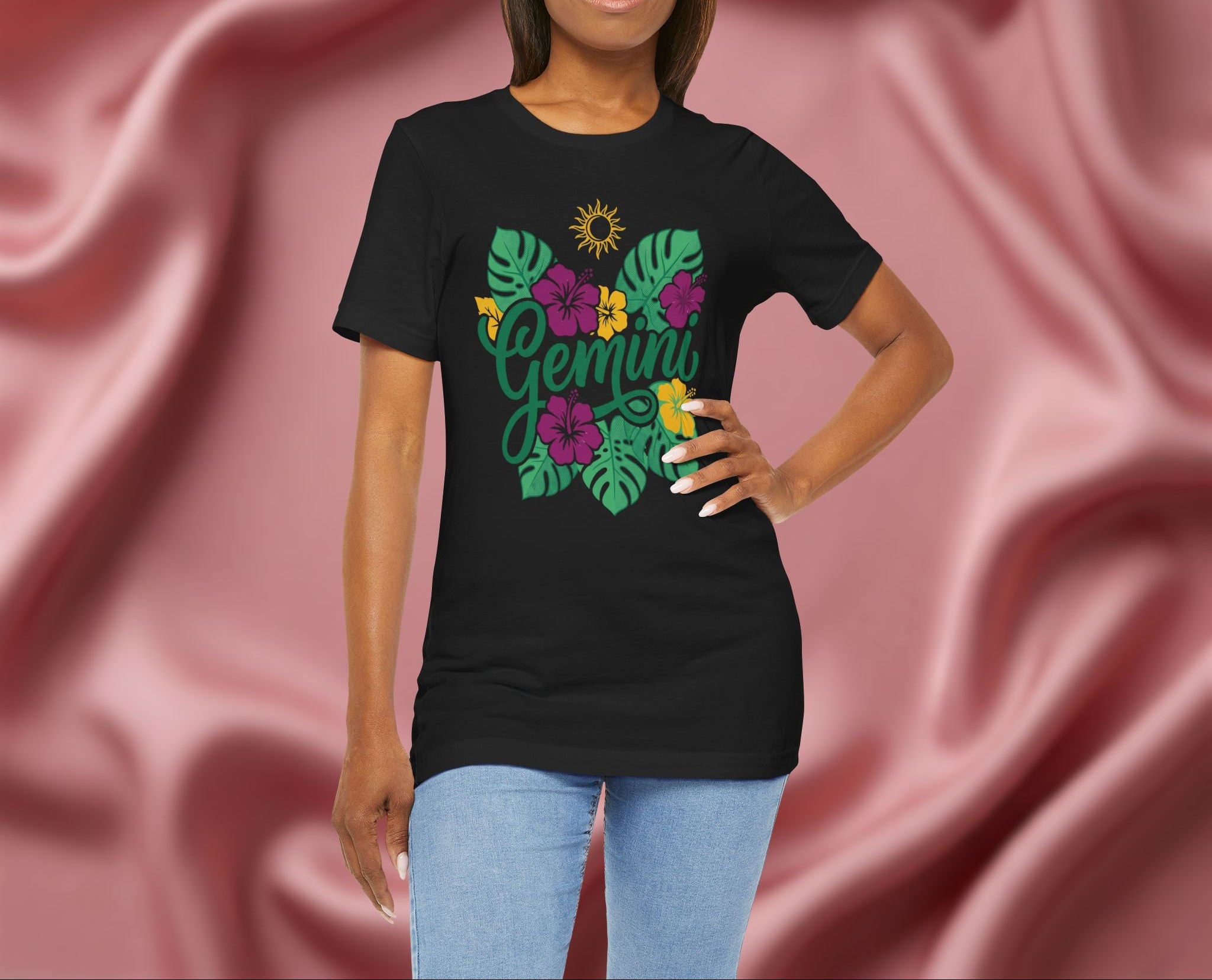 Woman wearing a black t-shirt with 'Gemini' design featuring flowers and leaves on a maroon fabric background