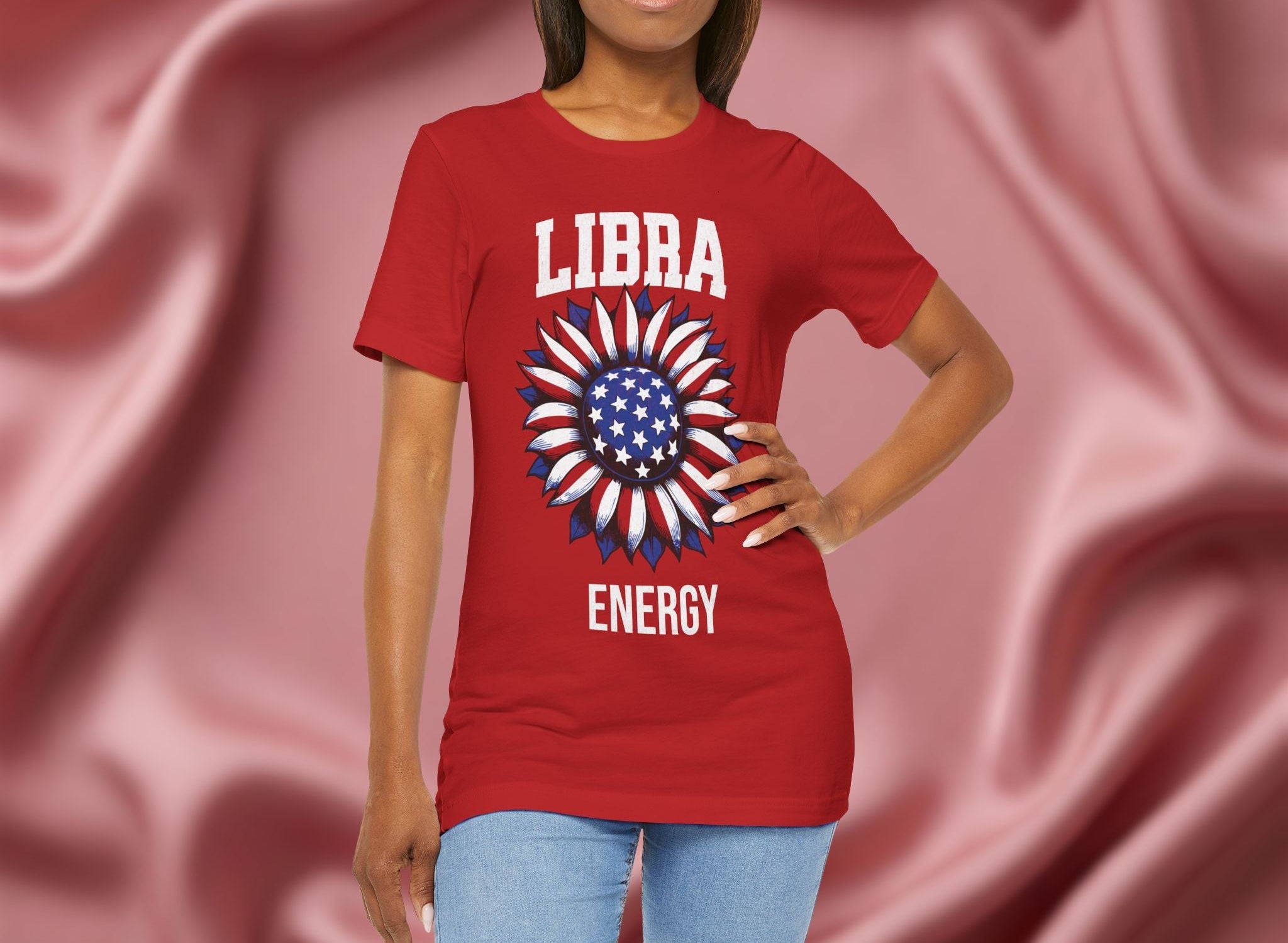 Person wearing a red t-shirt with American flag sunflower and 'LIBRA ENERGY' text on a textured pink background