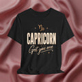 Black t-shirt with 'Capricorn Get you one' text on a pink fabric background