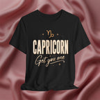 Black t-shirt with 'Capricorn Get you one' text on a pink fabric background