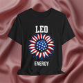 Black t-shirt with American flag sunflower and 'LEO ENERGY' text on a textured pink background