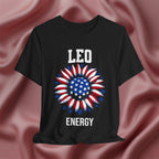 Black t-shirt with American flag sunflower and 'LEO ENERGY' text on a textured pink background