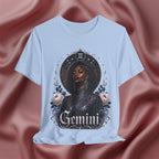 Light blue t-shirt with a graphic design of a woman, flowers, and the word 'Gemini' on a pink fabric background.