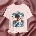 Soft pink t-shirt with 'Aquarius Too Weird To Care' design featuring a black woman wearing a t-shirt with the text 'different is my superpower' on a pink fabric background