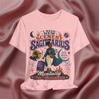 Pink t-shirt with Sagittarius zodiac design on a maroon fabric background