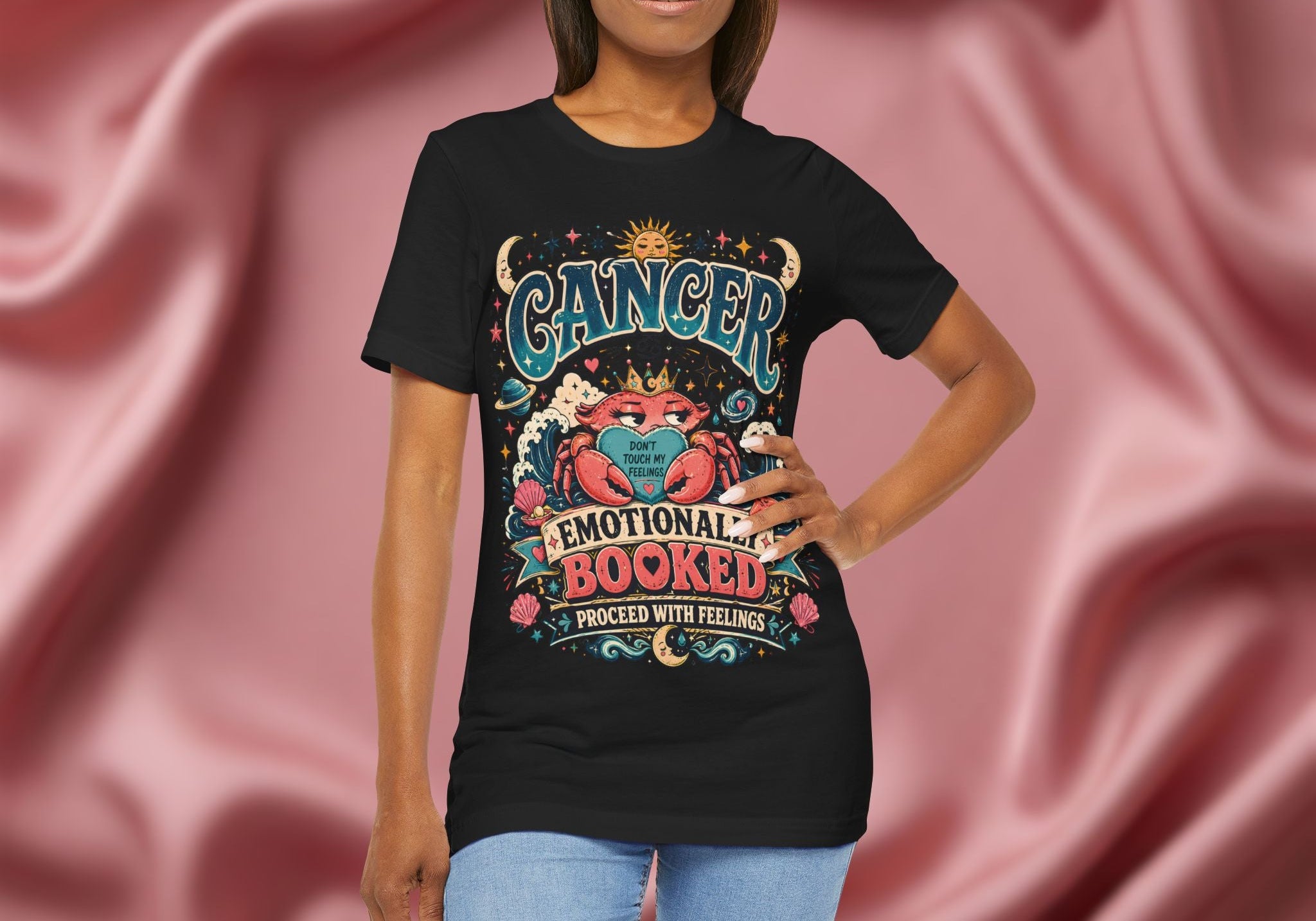 Person wearing a black t-shirt with 'Cancer' design against a pink fabric background