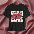 Black t-shirt with 'GEMINI Love' and lips design on a pink fabric background