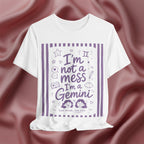 White t-shirt with purple text 'I'm not a mess I'm a Gemini and graphics on a pink fabric background