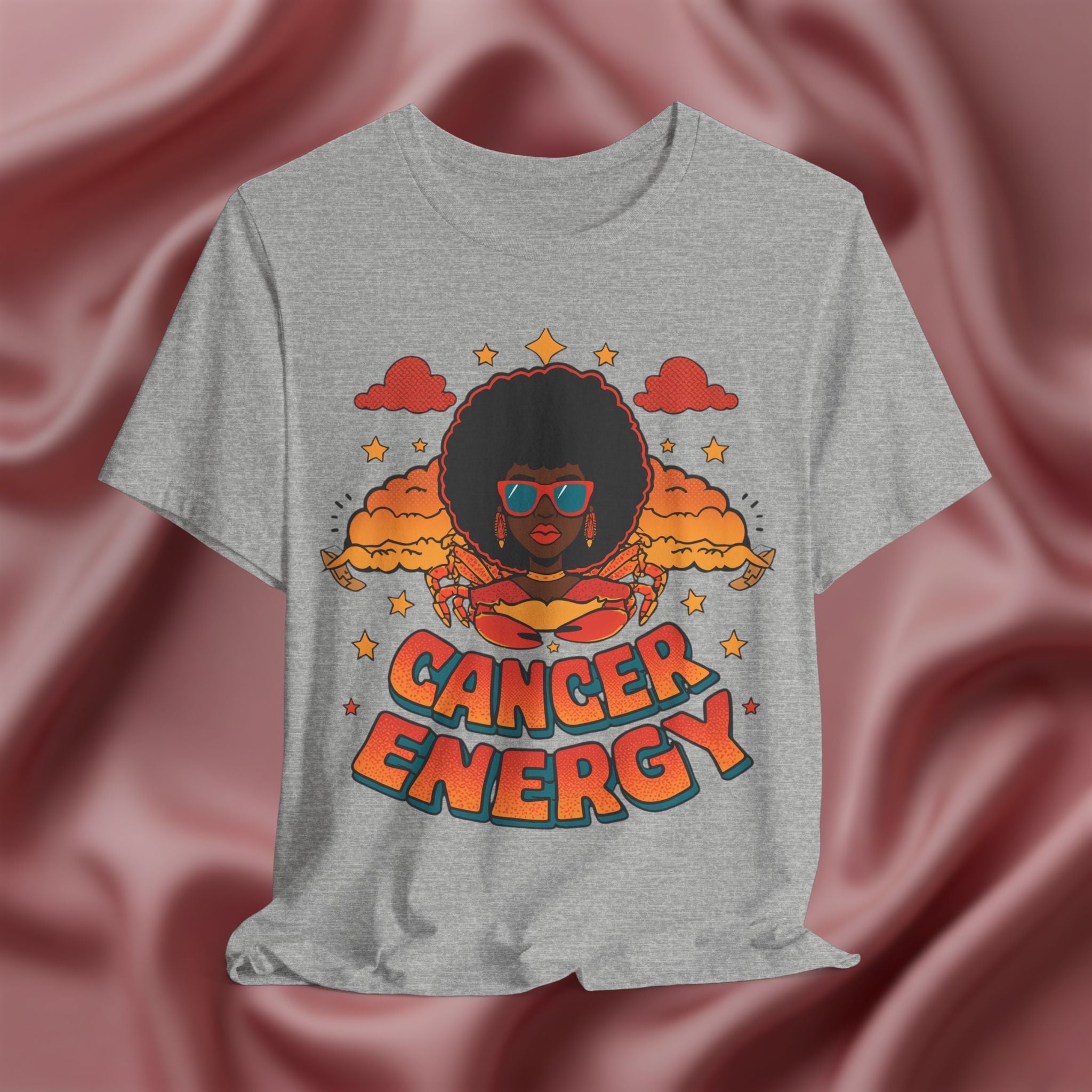 Gray t-shirt with a graphic design of a person with an afro and 'Cancer Energy' text on a pink fabric background.