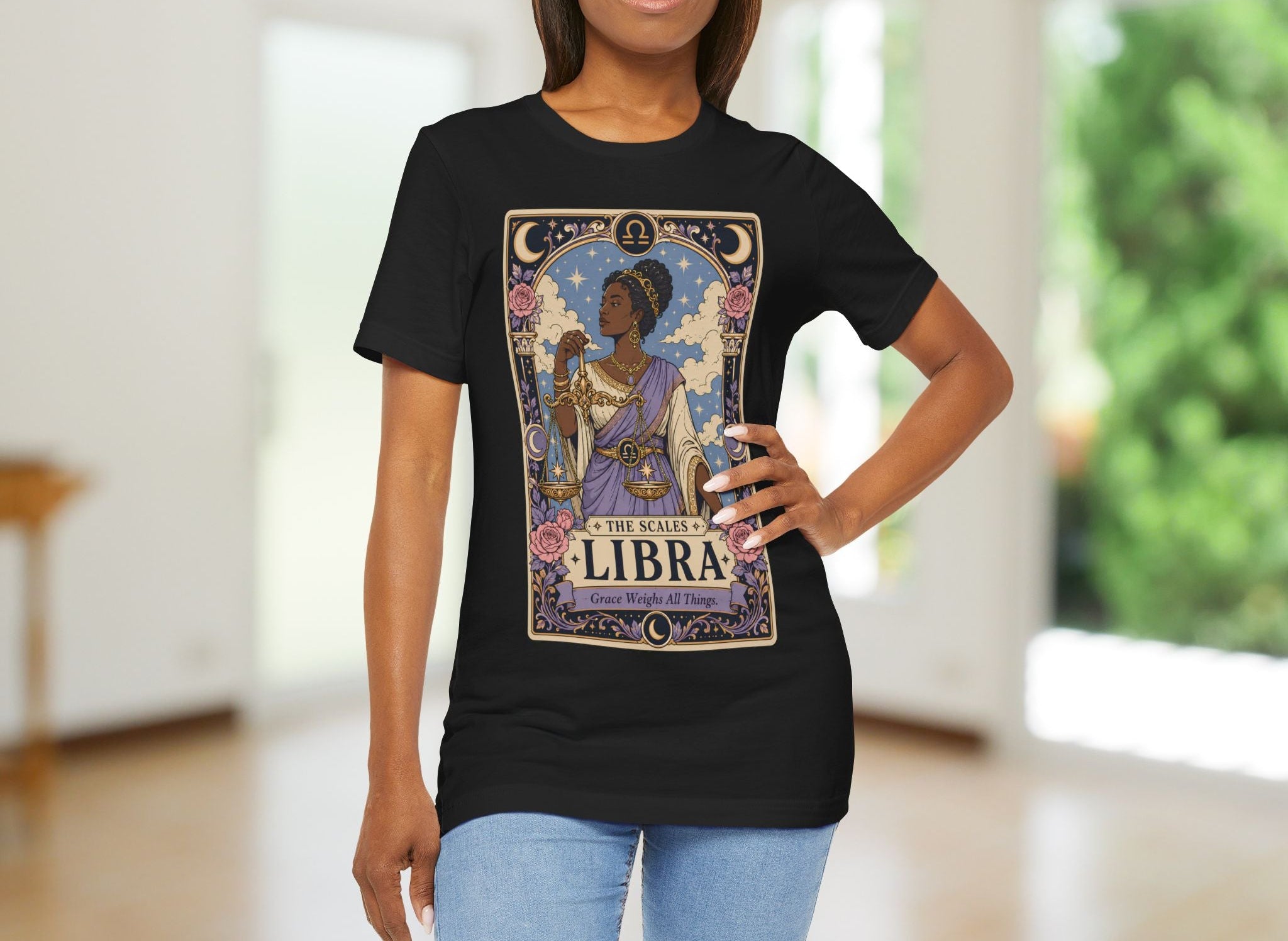 Woman wearing a black t-shirt with a Libra zodiac design in a room with blurred background