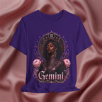 Purple t-shirt with a graphic design of a woman, flowers, and the word 'Gemini' on a pink fabric background.