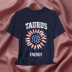 Navy blue t-shirt with American flag sunflower and 'TAURUS ENERGY' text on a textured pink background