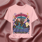 Pink t-shirt with Aquarius-themed design on a maroon fabric background