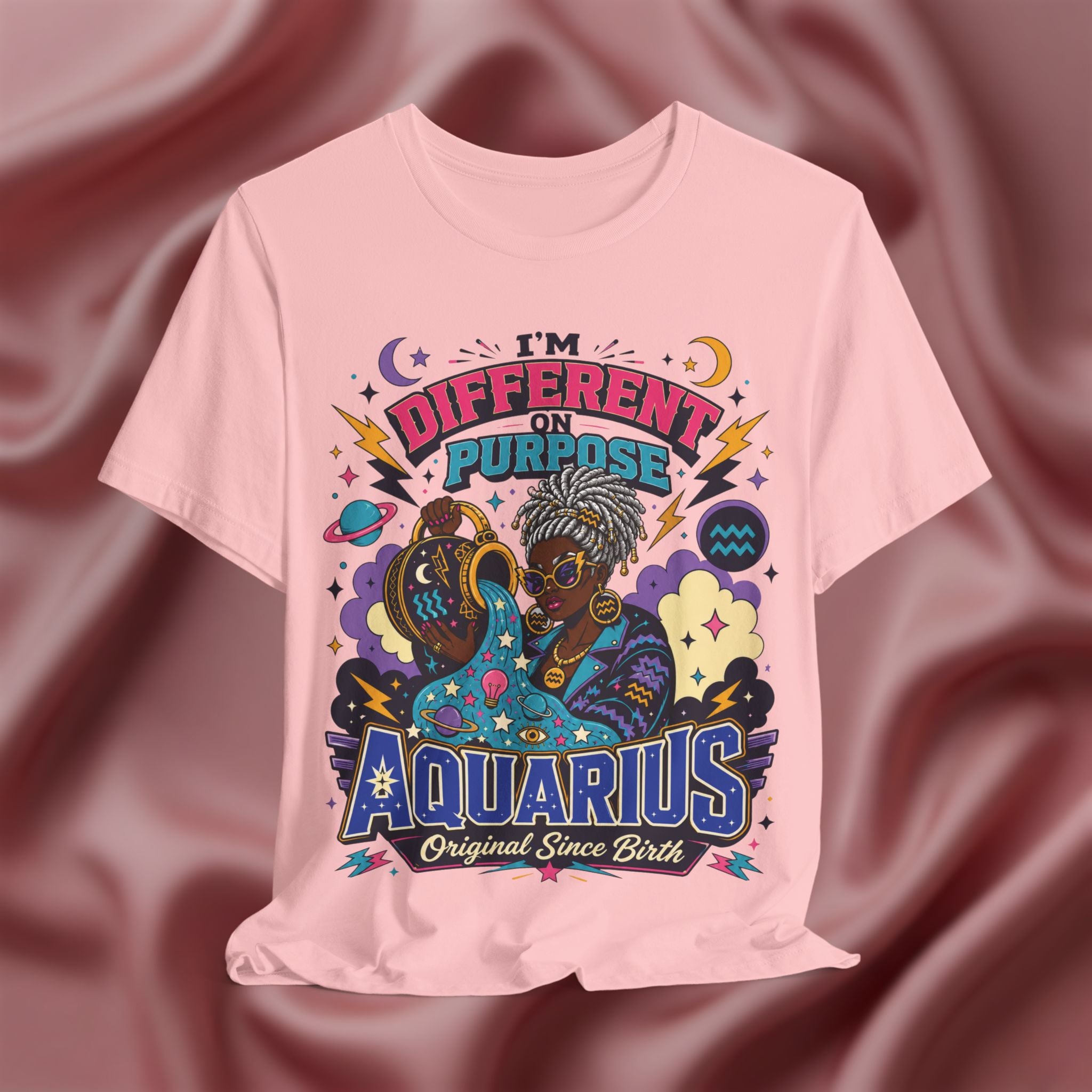 Pink t-shirt with Aquarius-themed design on a maroon fabric background