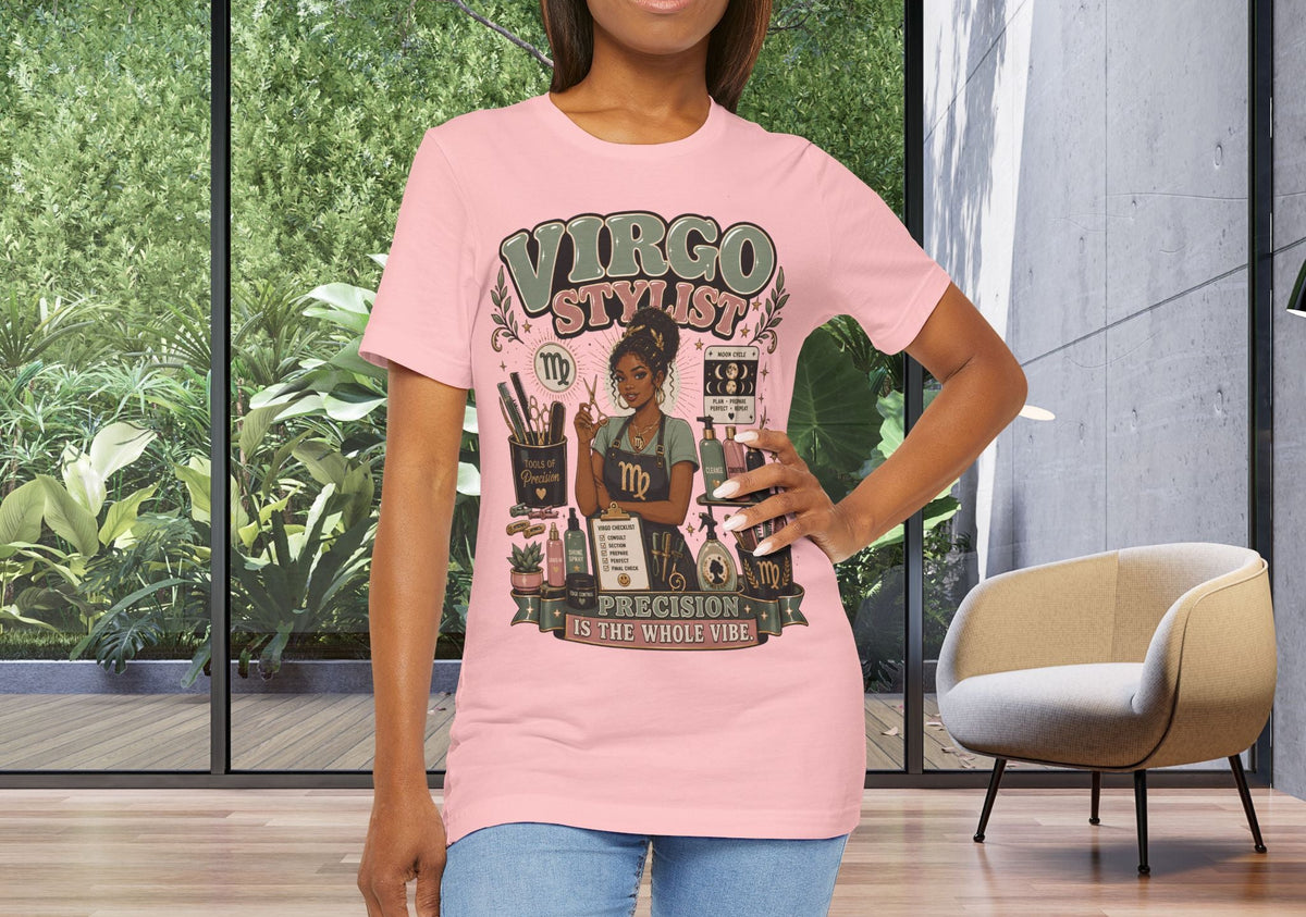 A woman modeling a light pink graphic t-shirt with a 'Virgo Stylist' design, standing in a modern room with large windows showing green foliage outside.