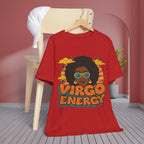 A red graphic t-shirt hanging on a wooden hanger against a pink wall and light wood chair backdrop. The shirt features a retro-style illustration of a Black woman with sunglasses, clouds, and the text 'VIRGO ENERGY' in orange and teal.