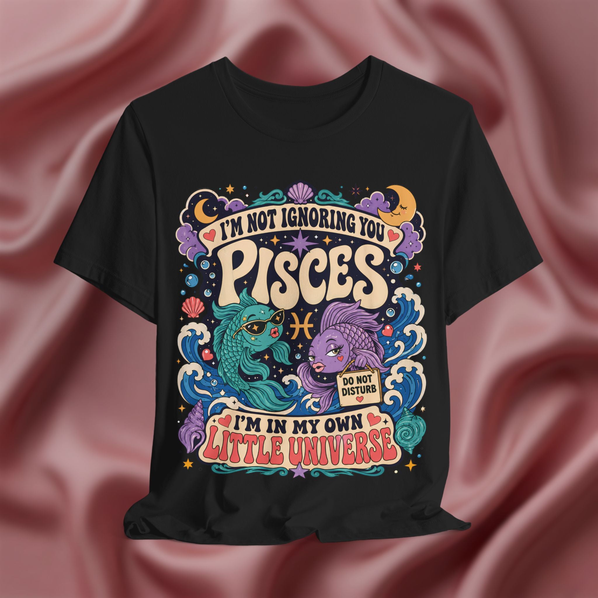 Black t-shirt with colorful Pisces zodiac design on a pink fabric background