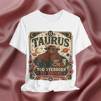 White t-shirt with Taurus zodiac design on a maroon fabric background