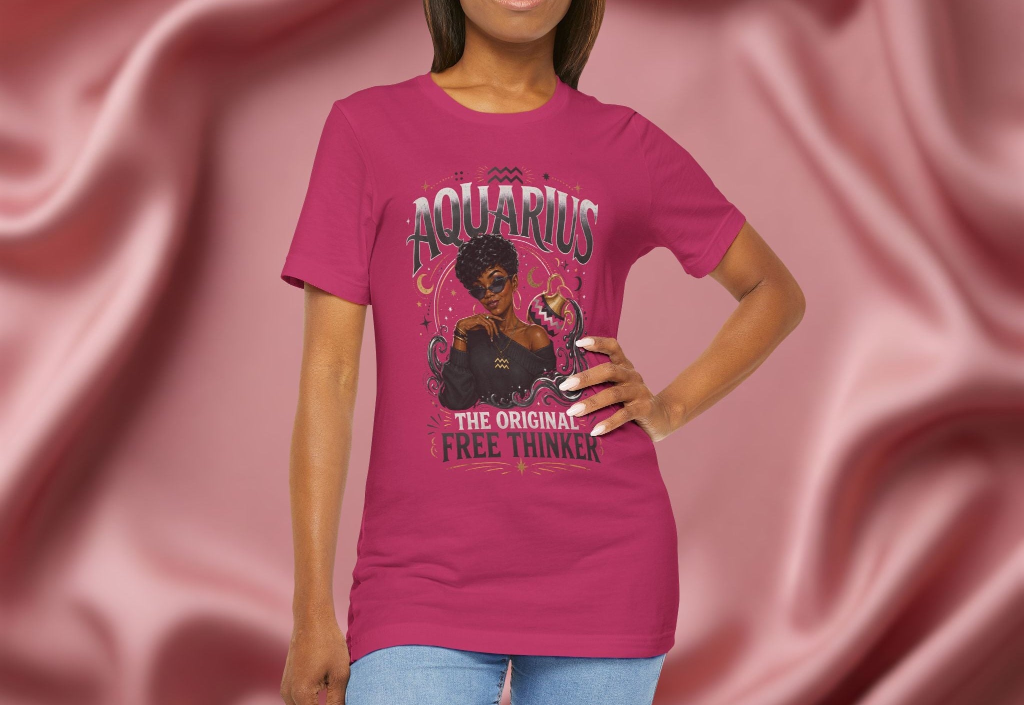 Woman wearing a pink t-shirt with Aquarius design featuring a black woman and text 'The original free thinker' on a pink fabric background