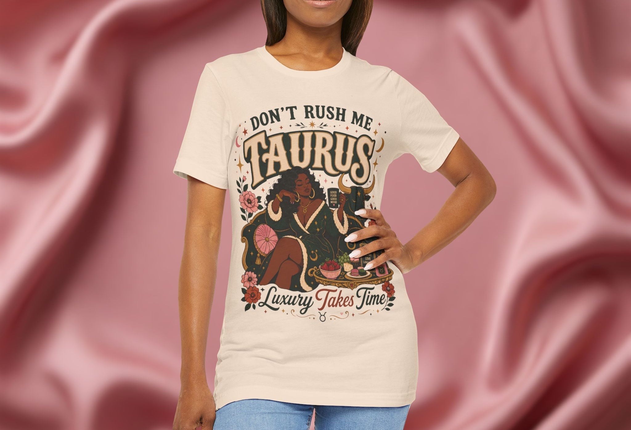 Woman wearing soft cream  a t-shirt with 'Don't Rush Me, Taurus, Luxury Takes Time' design against a pink fabric background