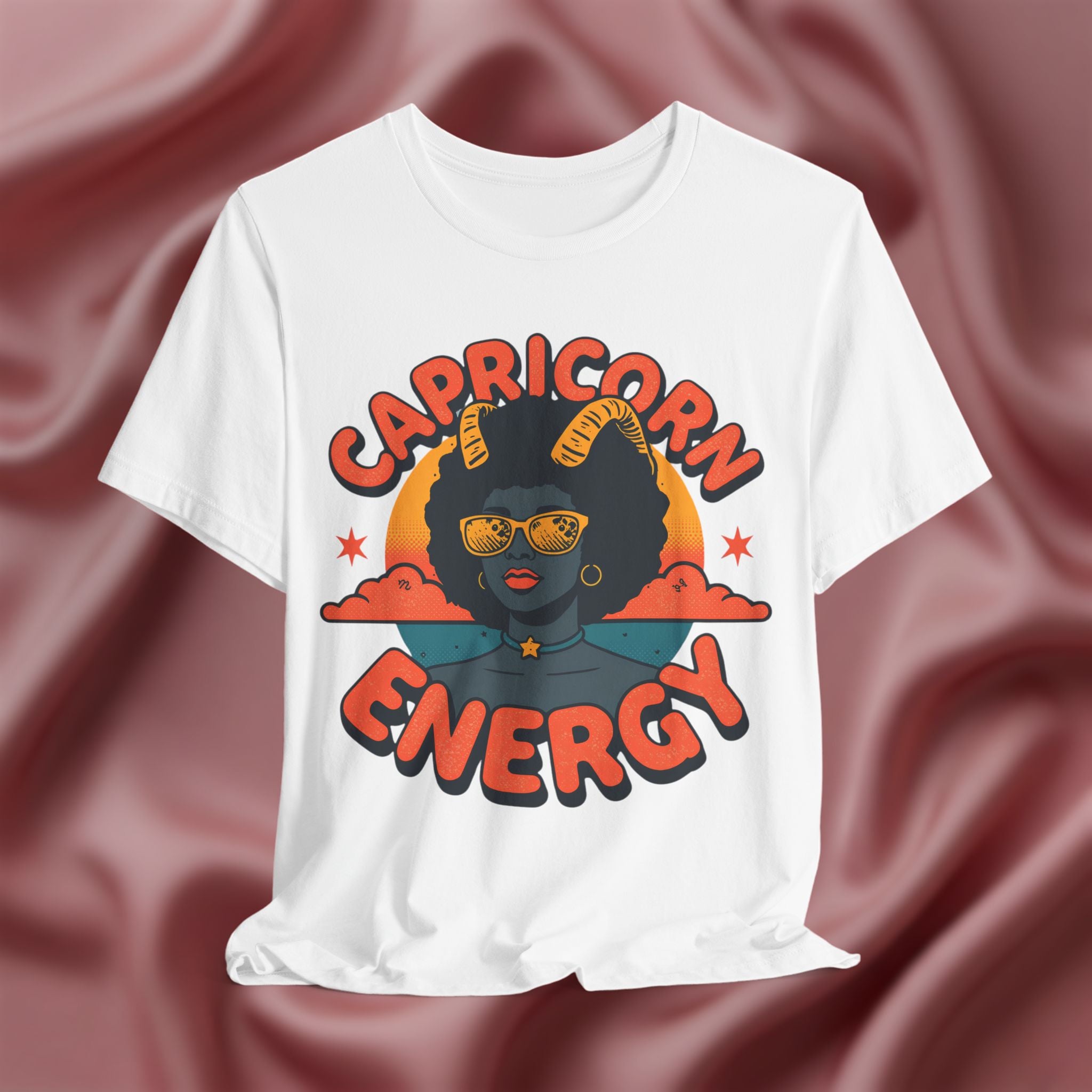 White t-shirt with 'Capricorn Energy' design on a maroon fabric background