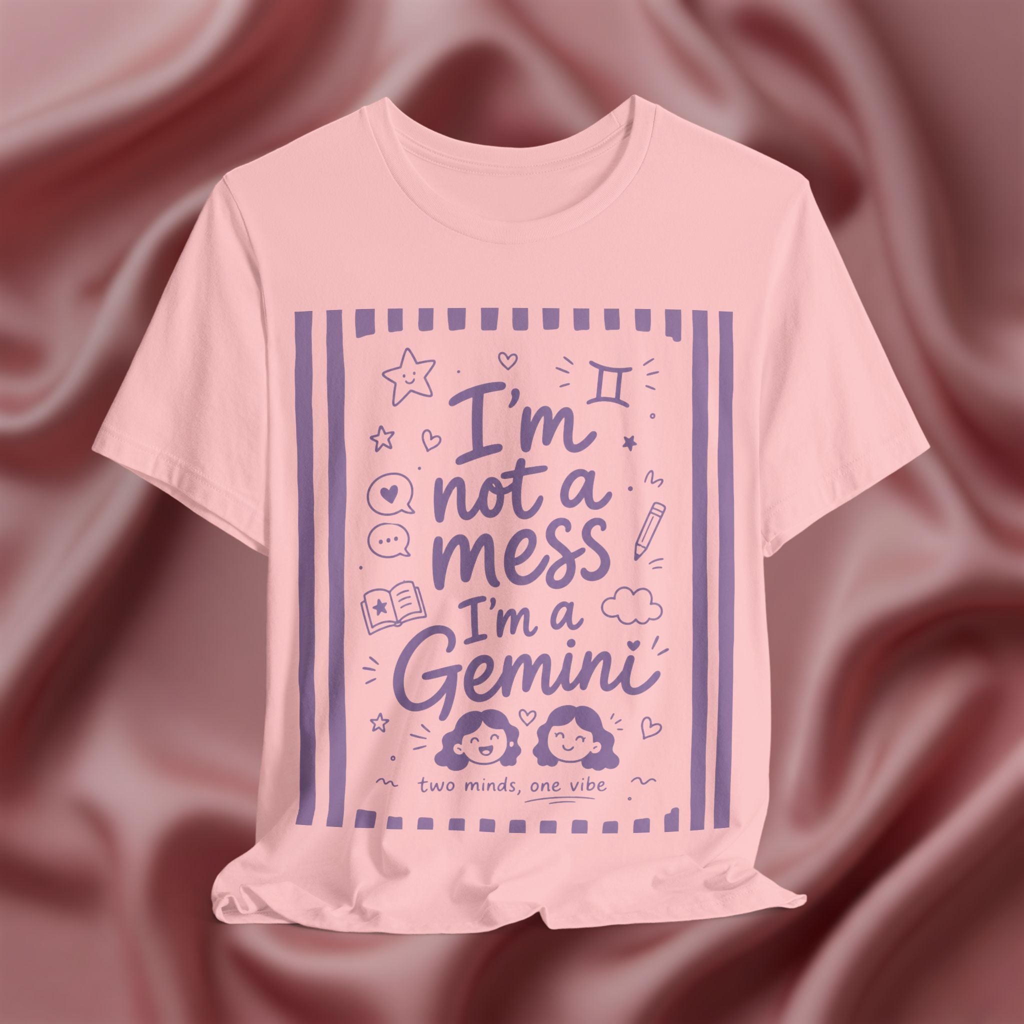 Pink t-shirt with purple text 'I'm not a mess I'm a Gemini and graphics on a pink fabric background