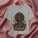Gray t-shirt with a graphic design of a woman's face, flowers, and the word 'Gemini' on a pink fabric background.