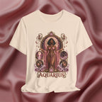 Cream T-shirt with 'Aquarius' design featuring a woman in a pink dress on a pink fabric background