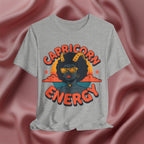 Gray t-shirt with 'Capricorn Energy' design on a pink fabric background