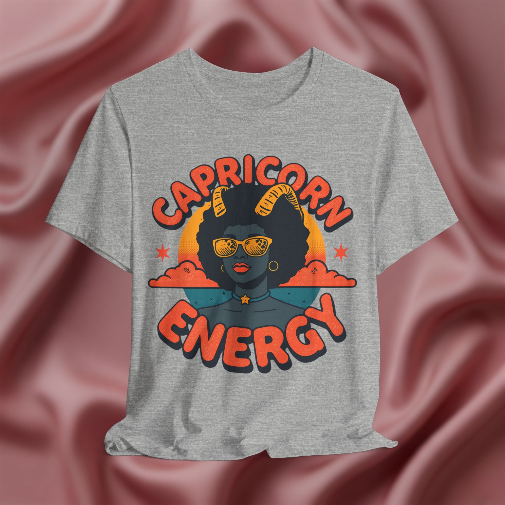 Gray t-shirt with 'Capricorn Energy' design on a pink fabric background