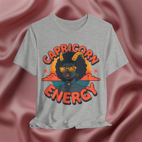 Gray t-shirt with 'Capricorn Energy' design on a pink fabric background
