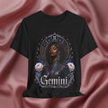 Black t-shirt with 'Gemini' design featuring a woman and astrological symbols on a pink fabric background.