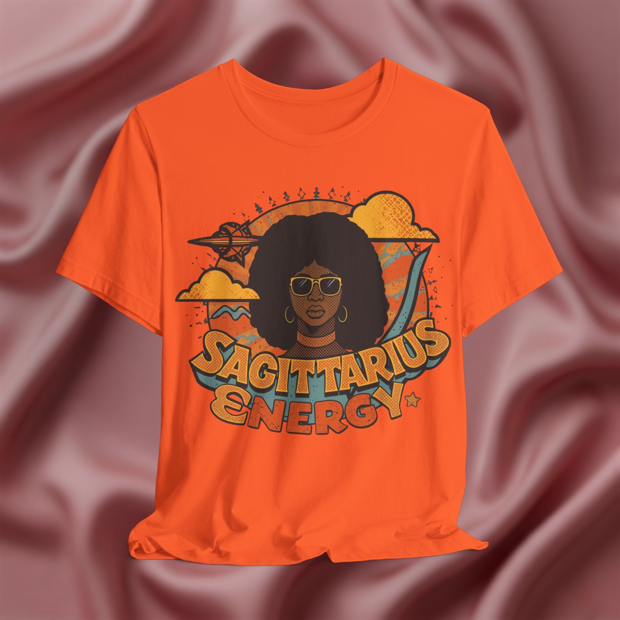 Orange t-shirt with 'Sagittarius Energy' design on a pink fabric background
