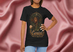 Woman wearing a black t-shirt with a graphic design of a woman, flowers, and the word 'Gemini' on a pink fabric background.