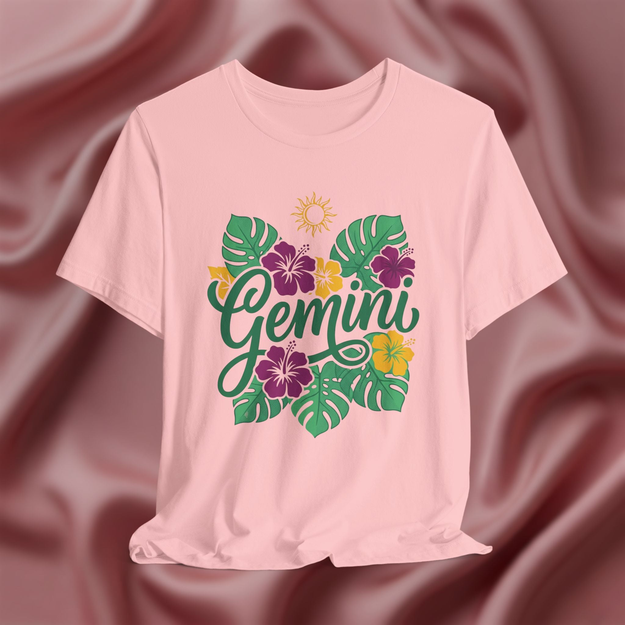 Pink t-shirt with 'Gemini' design featuring flowers and leaves on a maroon fabric background