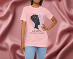 Woman wearing a pink t-shirt with a silhouette of a woman and 'Gemini Divinely Aligned' text on a pink fabric background
