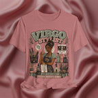 A heathered dusty rose pink graphic t-shirt featuring a 'Virgo Stylist' design, displayed on a draped satin fabric background.