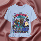 Light blue T-shirt with Aquarius design and text on a textured pink background