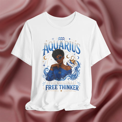 White t-shirt with Aquarius design featuring a black woman and text 'The original free thinker' on a pink fabric background