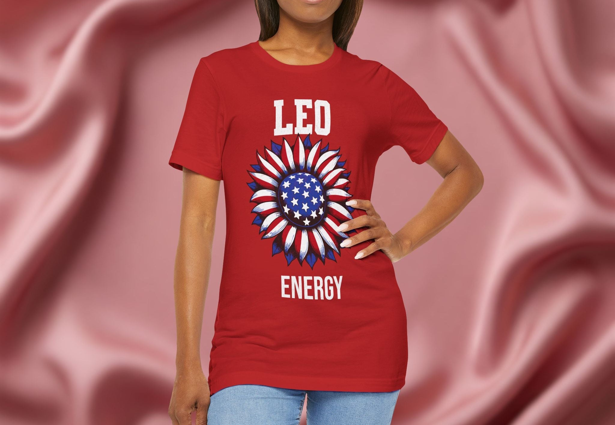 Person wearing a red t-shirt with American flag sunflower and 'LEO ENERGY' text on a textured pink background