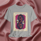 Sophisticated Queen Gemini Energy Gray t-shirt with a graphic design of a woman holding coffee cups on a pink fabric background