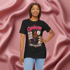Woman wearing a black t-shirt with Capricorn zodiac design against a pink fabric background