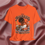 Orange t-shirt with 'Aquarius Too Weird To Care' design featuring a black woman wearing a t-shirt with the text 'different is my superpower' on a pink fabric background