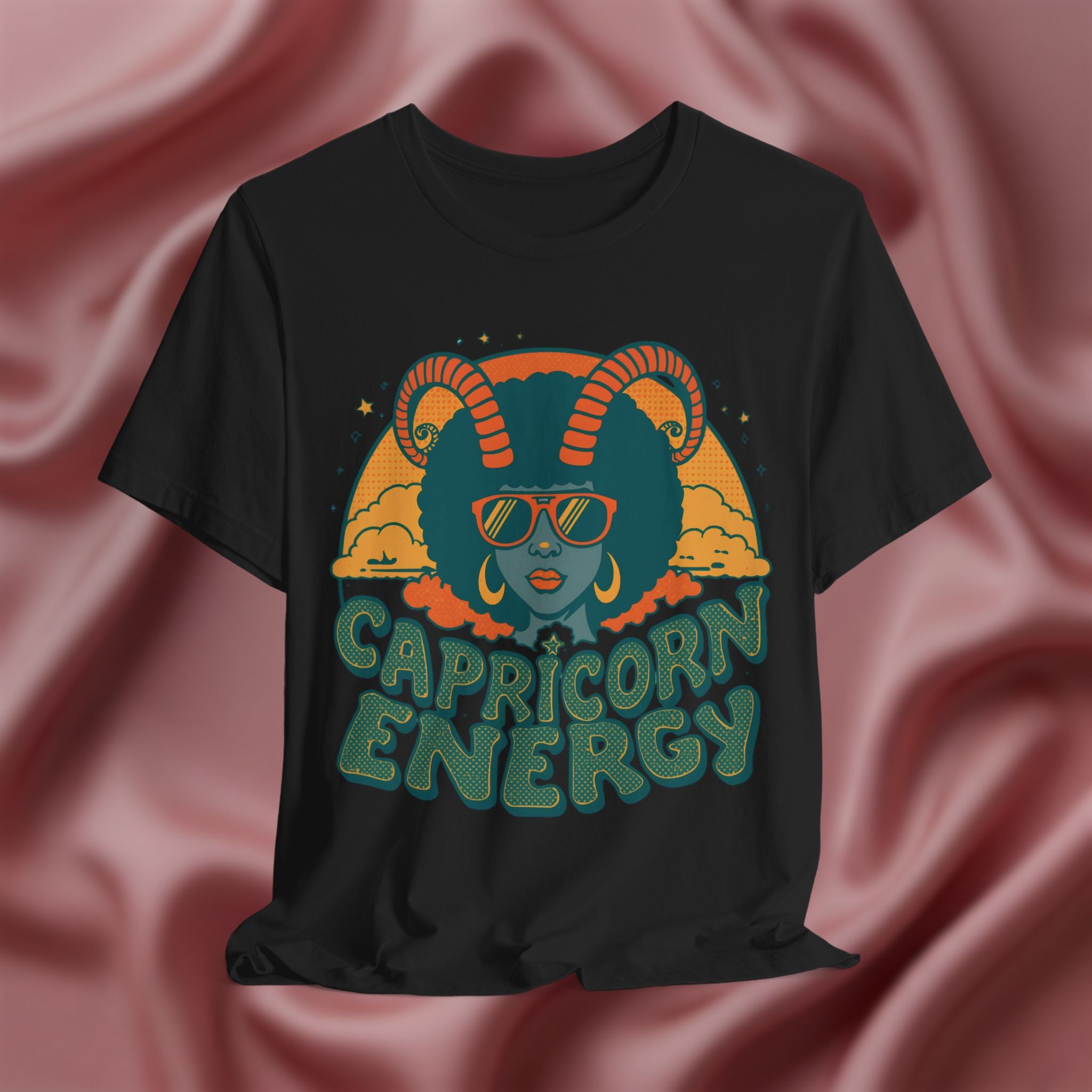 Black t-shirt with Capricorn design and 'Capricorn Energy' text on a pink fabric background
